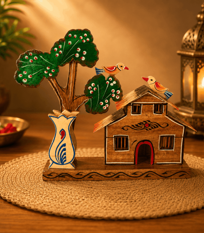 Handmade Wooden Village House Showpiece Bring the peaceful beauty of countryside living into your home with this handcrafted wooden village house showpiece. Carefully designed by skilled Indian artisans, this decorative masterpiece combines a traditional village house, vibrant birds, a handcrafted tree, and an elegant flower vase to create a charming display. Made from premium quality natural wood, every detail is hand-painted with care, giving each piece its own unique character. The rustic finish and traditional artwork make it an attractive decorative item for modern as well as classic interiors. Whether displayed on a living room table, office desk, bookshelf, TV unit, reception counter, or display cabinet, this handcrafted wooden décor creates a warm and welcoming atmosphere. Its timeless design also makes it an excellent gift for housewarming ceremonies, birthdays, anniversaries, weddings, festivals, and corporate occasions. A perfect collectible for anyone who appreciates authentic Indian handicrafts and handmade wooden art. Key Features Handmade by skilled Indian artisans Premium quality natural wood construction Beautiful village house with tree and birds design Hand-painted traditional artwork Eco-friendly and durable Lightweight yet sturdy Rustic finish for elegant interiors Suitable for home and office decoration Ideal gift for family, friends, and colleagues Unique handcrafted collectible Perfect For Living Room Decoration Office Desk Decor Study Table Decoration Bookshelf Display TV Unit Decoration Reception Counter Decor Housewarming Gift Birthday Gift Wedding Gift Festival Gift Corporate Gift Traditional Indian Home Decor Care Instructions Clean with a soft dry cloth. Avoid excessive moisture. Keep away from prolonged direct sunlight. Handle carefully to preserve the hand-painted finish. Product Specifications Attribute Details Material Natural Wood Product Type Handmade Wooden Village House Showpiece Style Traditional Indian Handicraft Finish Hand Painted Theme Village House with Tree & Birds Placement Living Room, Office, Shelf, Desk Gift Suitable Yes Country of Origin India SEO Keywords Handmade Wooden Village House Showpiece Wooden Village House Decor Wooden House Showpiece Wooden Home Decor Wooden Tree Decor Wooden Bird Showpiece Indian Wooden Handicraft Rustic Wooden Home Decor Handmade Wooden Decor Traditional Wooden Showpiece Village Theme Decor Wooden Table Decor Wooden Office Decor Wooden Shelf Decor Indian Heritage Decor Artisan Wooden Craft Wooden Decorative Item Wooden Gift Item Eco Friendly Wooden Decor Wooden Living Room Decor